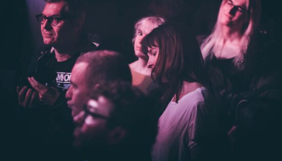 Photo de quelques personnes dans un public dont deux femmes écoutant la musique en fermant les yeux